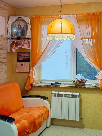 Оранжевый ретро абажур с бахромой висит в комнате