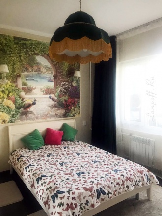 Зеленый большой абажур с бахромой над кроватью