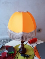 Оранжевая ретро лампа с бахромой на столике.