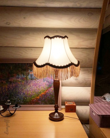 Ретро лампа с абажуром, на столе, включена.